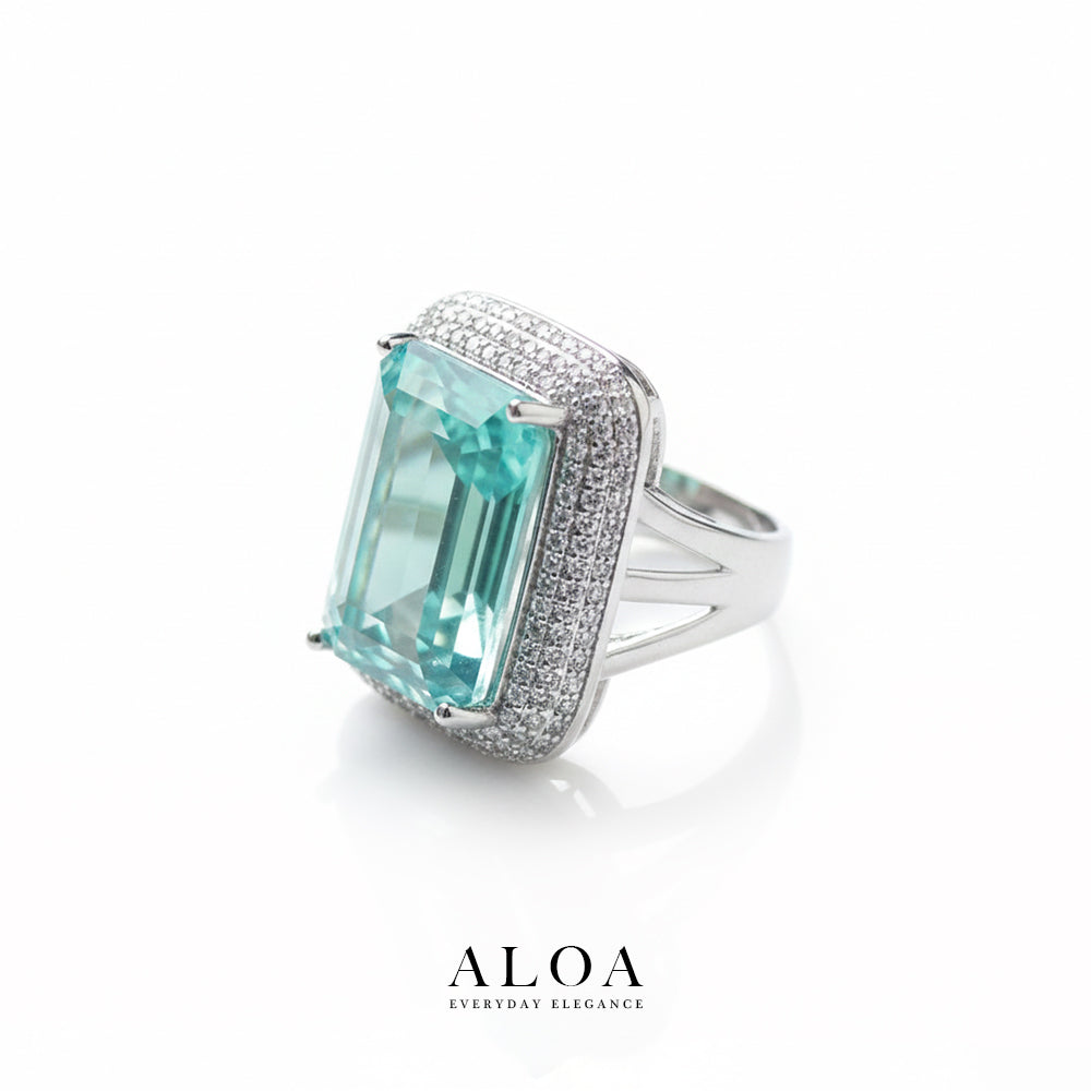 Luxury ring with a large aqua gemstone and diamond accents on a white background, featuring the brand 'ALOA'.