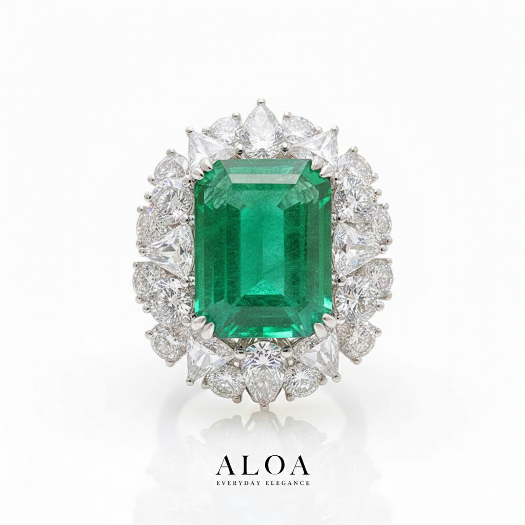 Emerald ring with diamond accents on a white background, featuring the brand 'ALOA'.